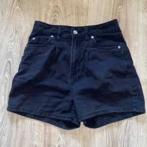 Svarta shorts från H&M - Säljer ett par svarta shorts från H&M i storlek XS. De är högmidjade och har klassisk design med knappar och dragkedja framtill. Perfekta för sommaren och kan matchas med nästan vad som helst. De är i bra skick och redo för en ny ägare!💕