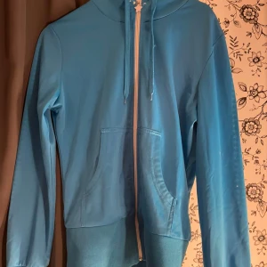 Blå hoodie med dragkedja - Säljer en snygg blå hoodie med dragkedja framtill. Den har en justerbar huva med snören och två fickor på magen. Perfekt för en avslappnad stil eller för att hålla sig varm under kyliga dagar. Passar bra till både jeans och träningsbyxor.  💙