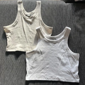 Två croppade linnen i vitt och beige - Säljer två croppade linnen i storlek (vit S) och (beige XS). Båda är ärmlösa och har en ribbad design. Perfekta för sommaren eller som basplagg i garderoben. De är i oanvänt skick och aldrig använda!🤍