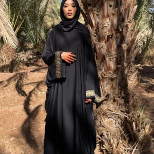 Svart långklänning med broderade detaljer - Säljer en elegant svart abaya med vackra broderade detaljer på ärmsluten. Ärmarna har även knappar på insidan. Klänningen har en lös passform och är perfekt för både vardag och fest. Den är tillverkad i ett mjukt och bekvämt material som faller fint. 