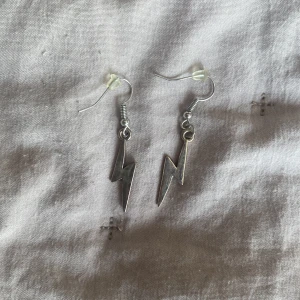 Blixtformade örhängen i silver - Säljer ett par coola blixtformade örhängen i silver. Perfekta för att ge din outfit en edgy touch! De är i nyskick och har en enkel krok för att hänga i öronen. Passar både till vardags och fest.