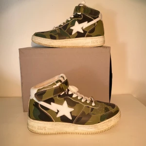 Bapesta Camo High-Top Sneakers - Hej, säljer ett par sjukt snygga Camo sneakers från Bapesta. Unika och sällsynta, slutsålt med samlarvärde. Kvitto från köp medkommer. Använda men fortfarande i fint skick. Storlek 42 och True To Size. Pris kan diskuteras. Hör av dig vid intresse! 