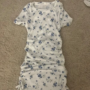 Vit sommarklänning, blåa blommor  - Vit sommarklänning med blåa blommor på, väldigt strechigt material, crunch på sidorna