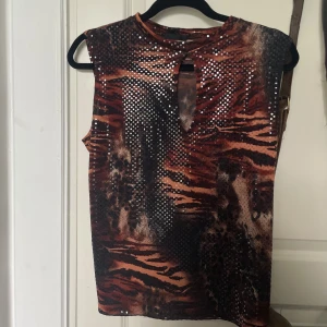 Linne med tigermönster & paljetter - Vintage linne i tigermönster med en urklippning i urringningen, hög krage samt genomskinliga paljetter som gör att den glimrar. Storlek står ej, men skulle säga runt L. Den är verkligen hur fin som helst, kommer bara aldrig till användning hos mig<3