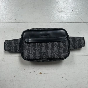 Lacoste Monogram Axelväska/ Midjeväska - Snygg axelväska/ midjeväska från Lacoste. Perfekt till sommaren. Inga synliga tecken på användning, perfekt skick. Skriv om du har frågor.