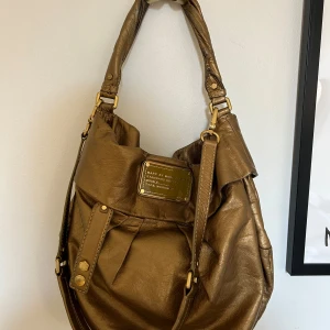 Marc Jacobs väska  - Säljer min Marc Jacobs väska då den inte kommer till användning. Väskan har ett fack på utsidan med dragkedja och en på insidan med dragkedja samt två så på insidan utan.  Väskan är medelstor och rymmer dator, skor, kläder perfekt skolväska.