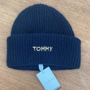 Blå mössa  Oanvänt med etiketterna kvar.  Guld ”Tommy” detalj som syns samt en annan detalj på baksidan som syns på bilden.  För dam men enligt mig passar både herr och kvinna.