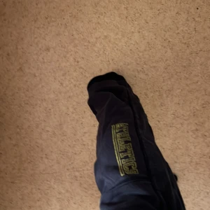 Mjukis byxor i den ikoniska 2000s stilen. - Svart/mörkblå färgad. Kortmidjad byxor för kortare tjejer (150). Ganska lösa och super bekväma. Kan användas i idrottslektioner eller till träningsaktiviteter.