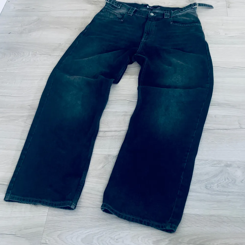 Ett par svarta jeansbyxor från Vicinity i storlek L (32L). Byxorna har en bred passform och är tillverkade i jeansmaterial. Byxorna har en midjejustering. Är använda ett par gånger men är som nya med minimalt slit nertill (bild 3). Org. Pris 1000kr. Jeans & Byxor.