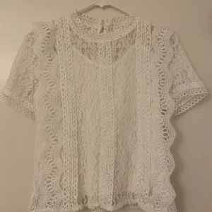 Vit topp med lace mönster - Vit t-shirt med lace mönster i nytt skick! (Bortklippt lapp)  Frakt tillkommer, kläder som köps kan samfraktas!