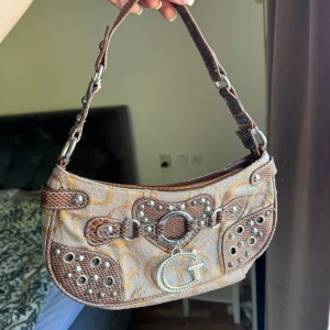 Guess väska - Säljer denna fina vintage Guess-väskan då den inte kommer till användning längre. OBS: dragkedjan går ej att stänga.