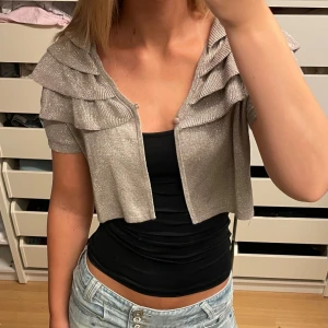 Glittrig bolero - Så himla fin lite glittrig bolero! Storlek M egentligen men skulle säga att den passar xs-m beroende på hur man vill att den ska sitta. Jag brukar oftast ha s eller m i tröjor!! Priset är diskuterbart