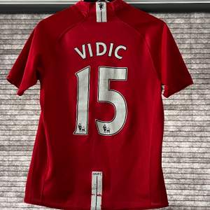 Tjena! Säljer en äkta Manchester United 2008 tröja med Vidic #15 på ryggen. Storleken är 158-170 cm så en barn XL och skicket är bra men det finns lite slitage på trycket på både fram och bak sida och några drag på fram sidan. Pm vid funderingar!😀