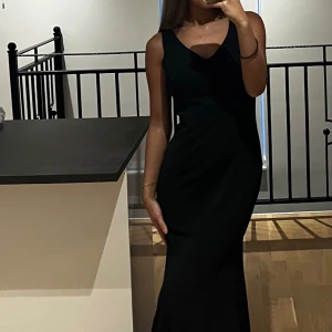 Aftonklänning  - Lång svart klänning med en uringning på ryggen.