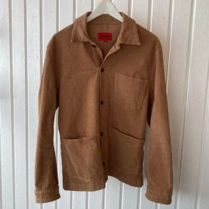 Overshirt i manchestertyg från Whyred - Overshirt från Whyred i brunt manchestertyg. Storleken är 48, herr men funkar såklart för dam också. Mkt fint skick, inköpt 2019 och använd ett fåtal gånger. 