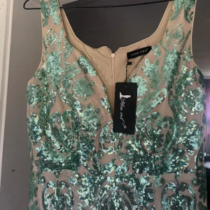 Grön och beige balklänning - Säljer denna fina balklänningen. Den är från shein men är bra kvalite ändå! Den är helt oanvänd, bara testad. Säljer den då jag hittade än annan klänning jag heller ville ha. Den är en aning stretchig och passar L-Xl skulle jag säga. Köpte den för ca