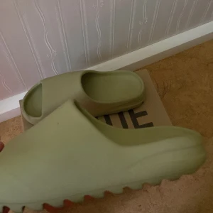 Yezzy slides - Säljer nu mina yeezy slides “resin” som passar perfekt inför sommaren, det finns inga skador och själv har jag storlek 42 och den sitter helt perfekt men 43 går också.