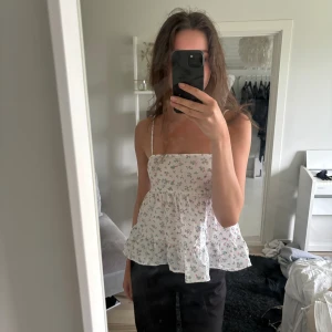 Topp - Blommigt linne med knytning baktill. Storlek s. Normal passform. Använt någon gång.