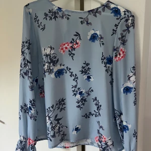Blommig blus - Blå blommig blus, sparsamt använd, knytning i ryggen