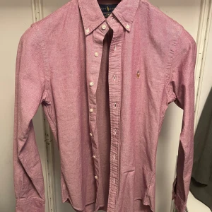 Rosa skjorta från Ralph Lauren - En rosa skjorta från Ralph Lauren i storlek S. Skjortan är slim fit i oxford-tyg. Endast använd enstaka gånger, mycket fint skick. 