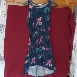 Klänning - Blå klänning med fågel och blommönster. Längre bak än fram. Armlös