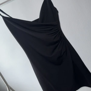 Svart klänning med slits - Svart superfin klänning med slits / öppning på sidan och dragkedja där uppe vid vikningarna / urringningen. Superfint skick, aldrig kommit till användning så därav säljer jag. Storlek S men passar även XS & kanske XXS/M beroende på kroppsform osv. 