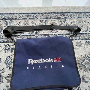 Vintage Reebok Classic väska - Säljer nu en fin väska från Reebok classic i bra använt skick! Se bilder! Snygg för sommaren👌 Mått: 45x35cm Hör av er vid frågor.