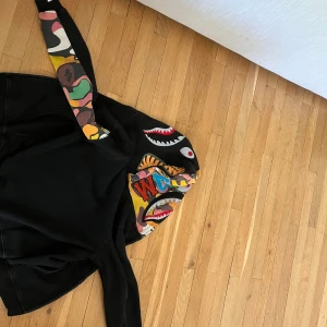 Svart Bape Zip Up - Den är köpt 2018 så ingen aning vad den heter eller original priset på den! Den är knappast använd, så den har legat några år i garderoben så den är i hyfsat skick! Skriv till mig om du har frågor eller vill ha mer bilder. Priset är ej hugget i sten. Dragkedjan är sönder.