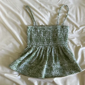 Utsvängt linne från Gina tricot - En grön och vit blommigt linne ifrån Gina tricot i storlek xs. Banden går Ven att ta av och sätta på eftersom de inte är fastsydda utan är fast med en ”krok”. Är använd 3 gånger ish och har inga hål.