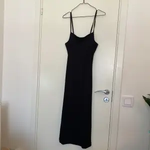 En svart ribbad klänning från H&M i storlek S. Öppen rygg med knytning 