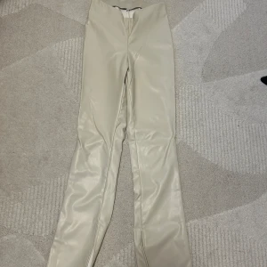 Skinnbyxor  - Beige skinn byxa med slit från H&M i storlek 38. Säljer pga att den blivit för stor. Använd ett fåtal gånger men fortfarande i jättebra skick.  