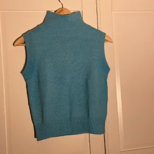 Stickad väst - Stickad turkos väst från NAKD med lite högre krage. Endast använd en gång.