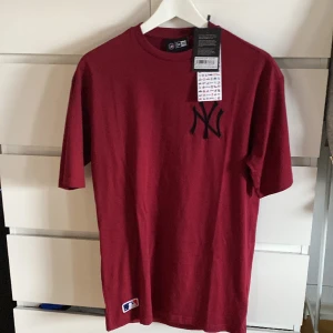 T-shirt från New Era - Vinröd t-shirt i xs men sitter som M eller stor S. Köpt på zalando för ca 400kr men säljer för den va för stor. Aldrig använd