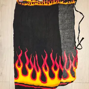 Beskrivning: Svart sarong med flames Märke: EMP Storlek: One size Skick: I mycket gott skick Material: 100% viskos  Nakenkatt finns i hemmet