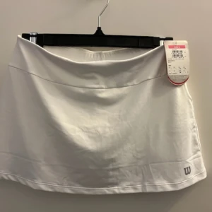 Tenniskjol Wilson - Superfinnnn vit tenniskjol med inbyggda shorts. Oanvänd!!!!! Barnstorlek! Skulle säga att den är lågmidjad och ganska kort. 