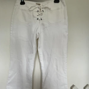 Utåtsvängda vita jeans  - Ett par utåtsvängda jeans i storlek 38/ M. Längden är lite förlorat för mig som är 168 cm, skulle kunna tänka mig att dem passar någon runt 160-165. Dem har även en liten gul fläck uppe vid byxkanten. Säljer då det inte passar mig i längden!