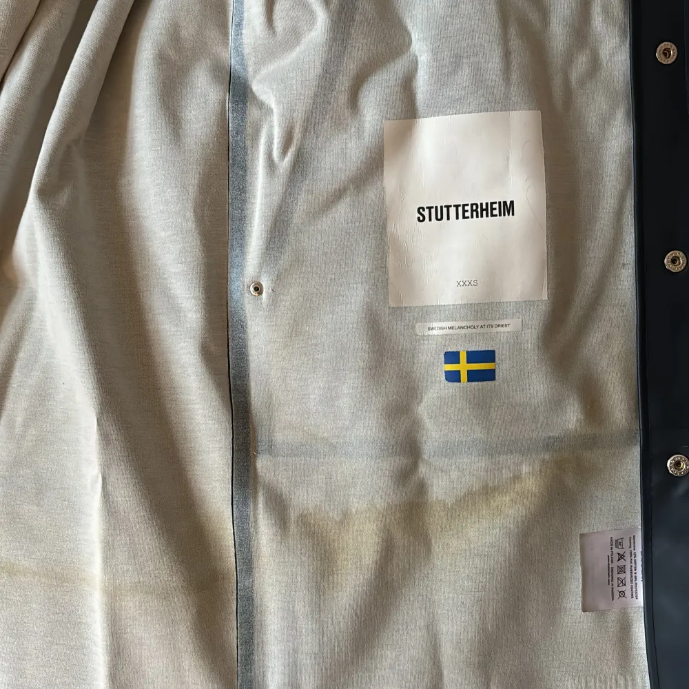 Mörkblå Stutterheim regnjacka. Sparsamt använd i mycket gott skick. Viss missfärgning på insidan (se bild). Storlek XXXS. Jackor.