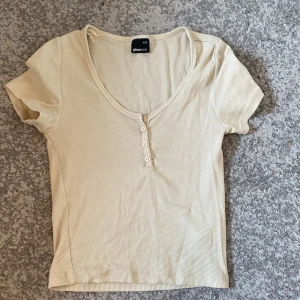 Uringad t-shirt - En beige t-shirt som är uringad och har 3 knappar. I bra skick! Pris går att diskutera.