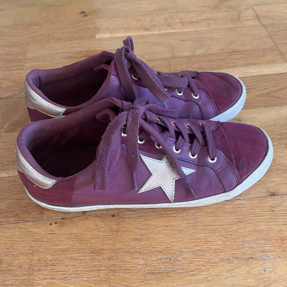 vinröda sneakers med stjärnor som detaljer på vardera sko. Storlek 40 . Skor.