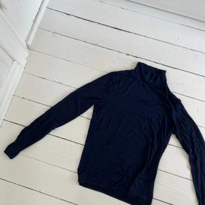 Mörkblå långärmad tröja med liten krage. Materialet är tunt och skönt