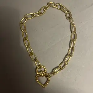 Halsband i guld. Låset är format som ett hjärta. 