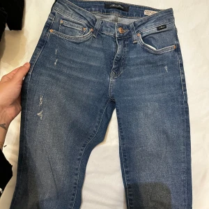 Mavi jeans  - Blå/mörk blåa jeans i storlek xs Raka ner till med slitningar  Fint skick , säljer då det ej passar mig längre 