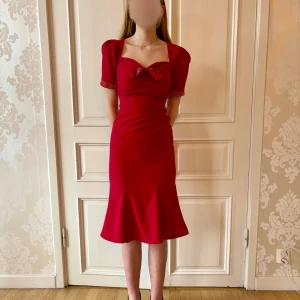 Röd klänning, Stop Staring! - Fin röd klänning i skönt material. Röd-vit-prickiga detaljer. Storlek M. Knytbart band.  Modellen på bilden är 173 cm, har storlek 38 i de flesta andra kläder. Aldrig använd. Vi har lagt ner vår klänningsbutik och säljer ut. Ny pris är 2000-3000k