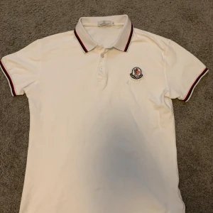 Moncler Pike  - Vit Moncler Piké. Äldre modell och därav är den lite urtvättad Storlek XL men Moncler har alltid haft små  i storleken + krympit i tvätten. Passar både S-M 
