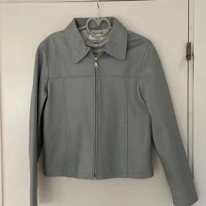 Kort jacka med krage - Kort jacka med krage i skinnimitation. Jacken är i fint skick utan några märken eller annat. 