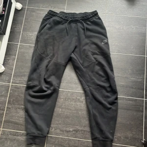 Nike tech byxor - Hej! Jag säljer ett par Nike tech byxor i svart:) det är några fläckar som knappt syns när man har på sig byxorna,därav priset. Äkta såklart!! 