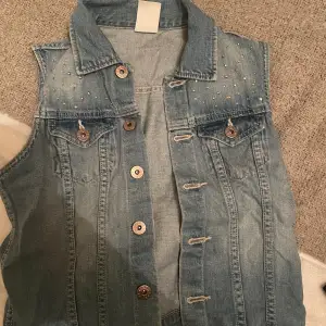 Jag säljer denna kortärmade jeans västen som har coola detaljer ibak och är perfekt tilll ett vitt linne storlek 170 men passar xs/s