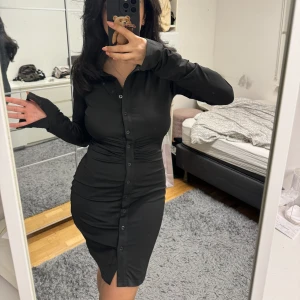 Skjortklänning - Skjortklänning i satin liknande material, den är jätte stretchiga. Har slits i Armarna 