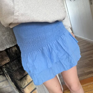 Populär mango kjol - Volangkjol från Mango i en såå fin blå färg som är slutsåld. Smockad i midjan och stretchig, passar mig med xs också. 55% linne och 45% viskos. Längd ca 42cm, midjemått ca 31,5cm (stretch).