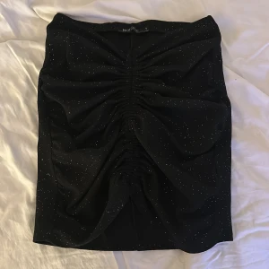 glittrig kjol - en glittrig kjol som passar perfekt till fest! endast använd en gång, har klippt av snörena en bit för jag tyckte att dom va för långa🖤 se bild 3 för att se hur snörena ser ut nu! nypris 350
